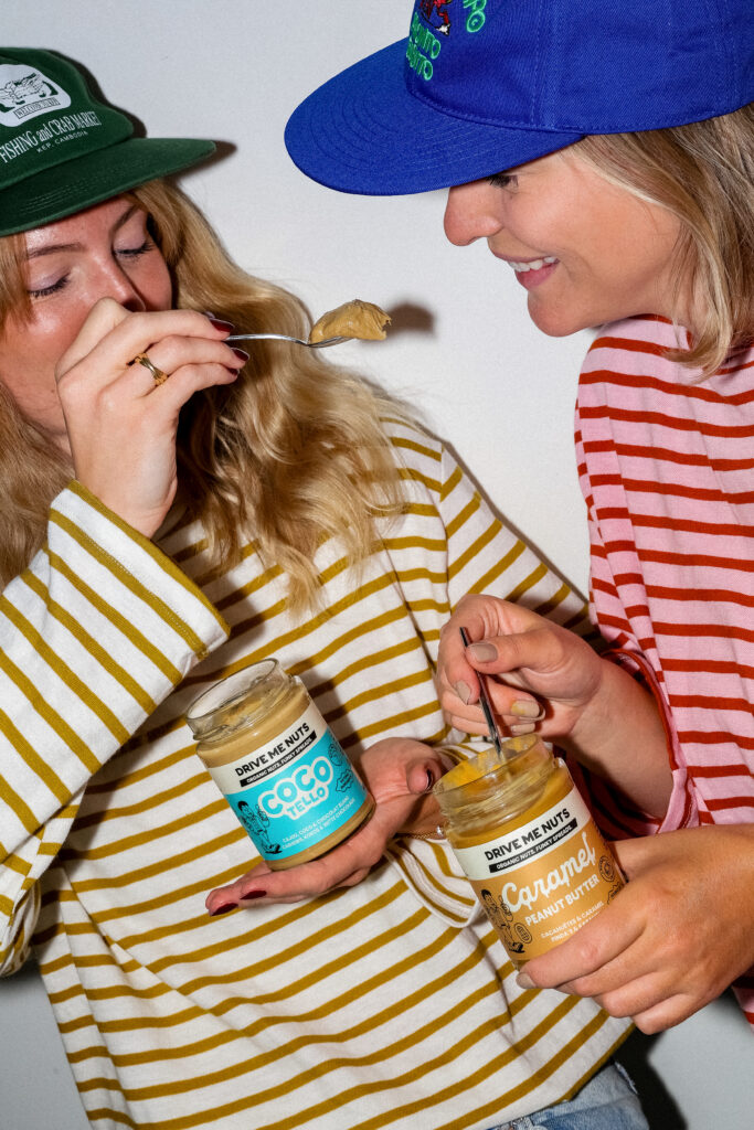 Two friends laughing with jars of Drive Me Nuts spreads